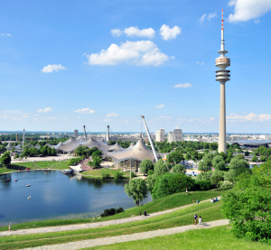 Blick auf den Olympiapark und Fernsehturm in München bei blauem Himmel.