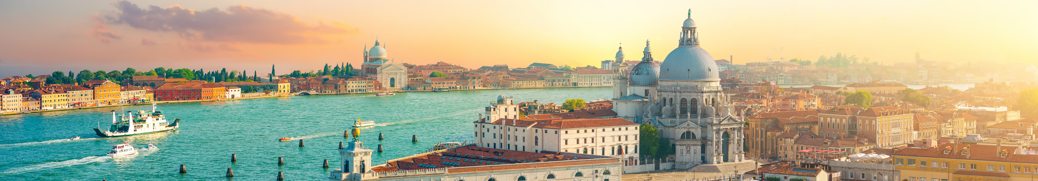 Panorama von Venedig mit der Basilica di Santa Maria della Salute und Booten auf dem Canal Grande bei Sonnenuntergang