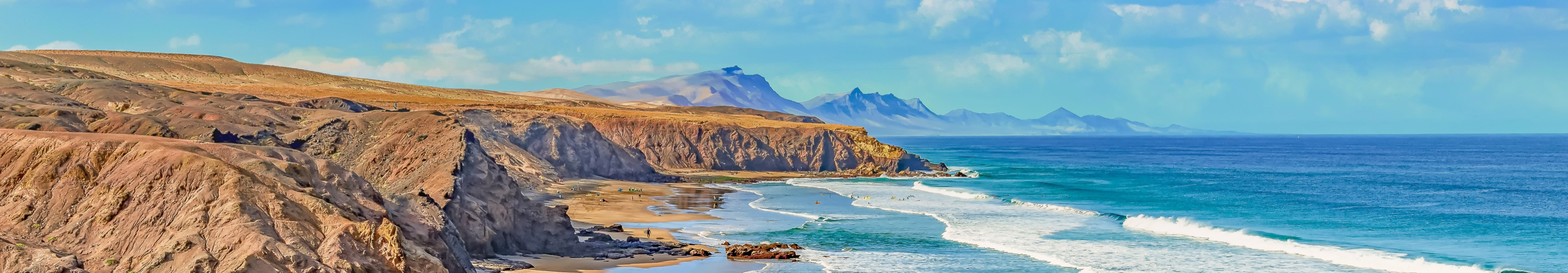 Weitl&auml;ufiger Sandstrand mit Felsklippen und t&uuml;rkisfarbenem Meer auf Fuerteventura, Kanarische Inseln.