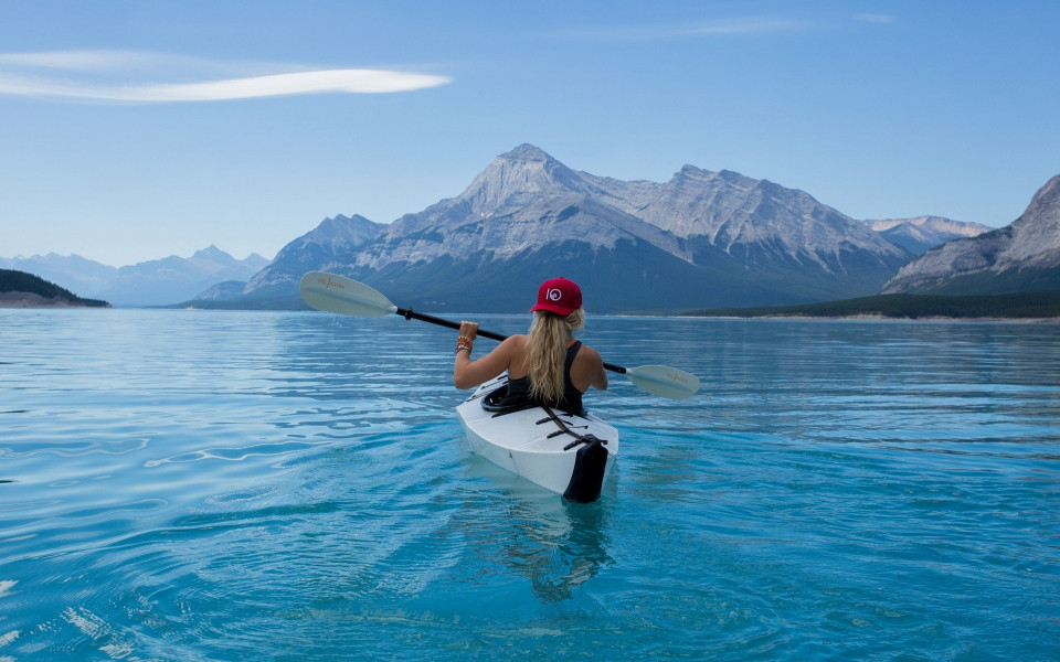 Frau f&auml;hrt Kanu auf einem See mit Bergkulisse