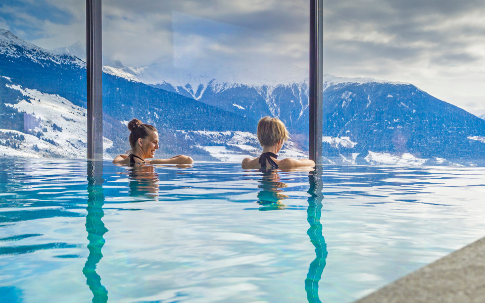 Zwei Frauen entspannen im Pool mit Blick auf die bayerischen Alpen