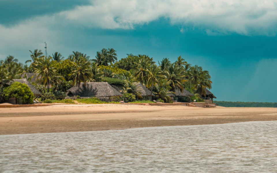 Idyllischer Strand mit Palmen und traditionellen Hütten auf Manda Toto Island.
