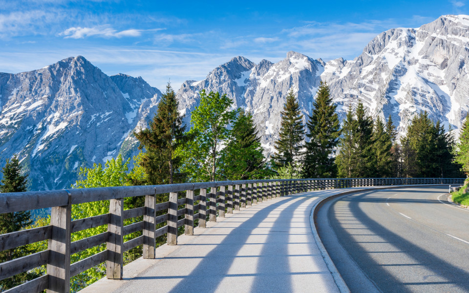 Autoleere Rossfeld Panoramastraße mit Blick auf die umliegenden Bergketten bei Sonnenschein.