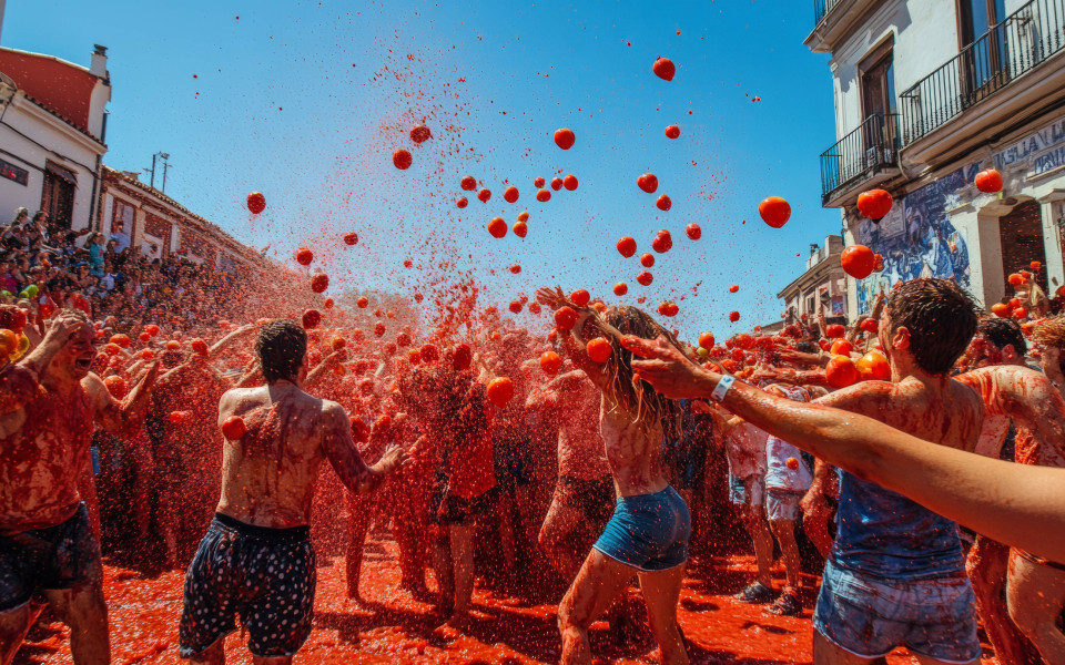 Menschen auf den Stra&szlig;en bewerfen sich mit roten Tomaten bei dem Fest La Tomatina in Spanien