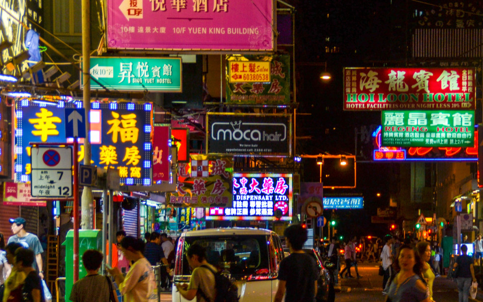 Beleuchtete Straße in Hongkong bei Nacht mit vielen bunten Schildern